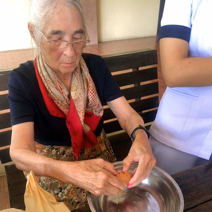 A resident being helped to wash rice by a carer.