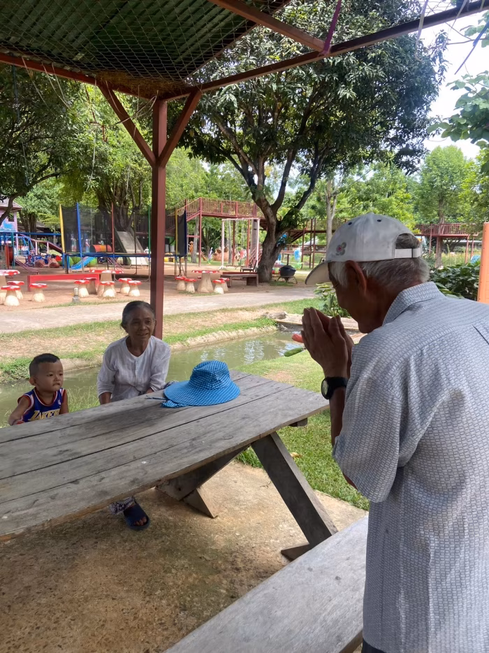 A resident standing with hands together at an outdoor pavilion.