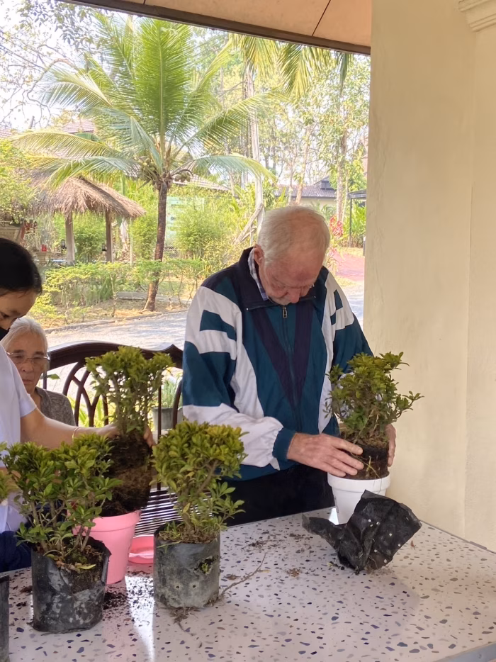 A resident seated with a carer and another resident indoors.