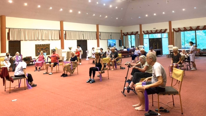 Residents on gym equipment, supervised by staff.