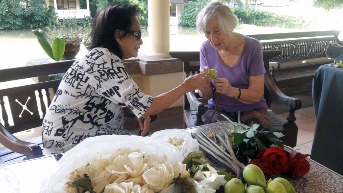 A carer presenting flowers to a resident on the terrace.