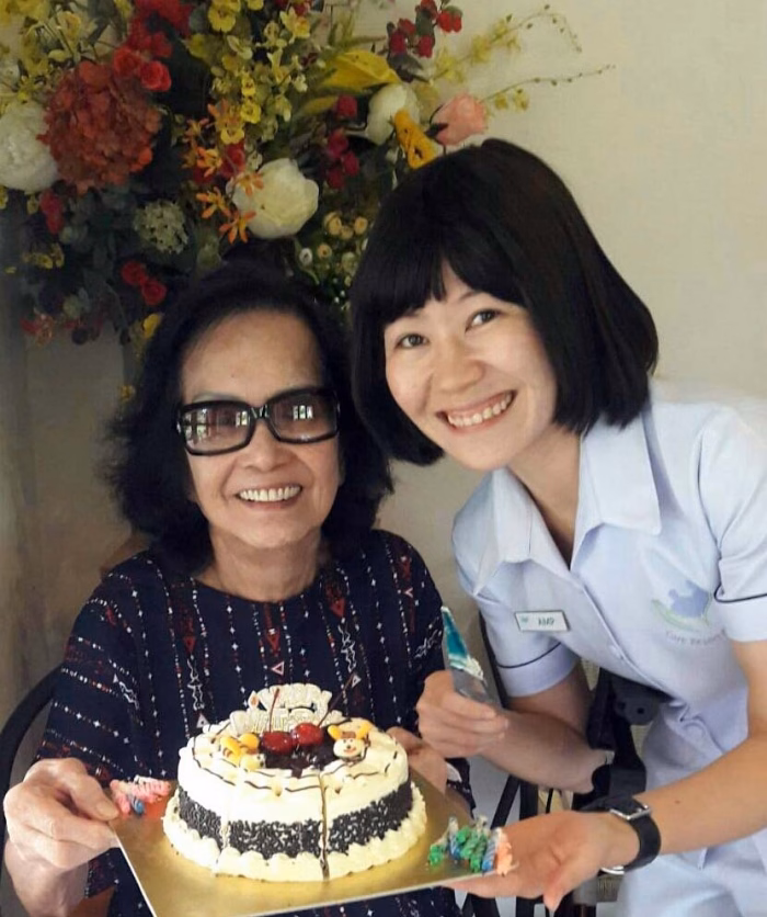 Two residents with a birthday cake indoors.