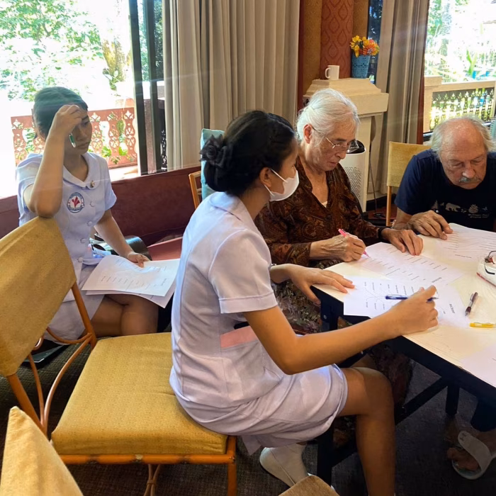 Residents and staff at a table with paperwork.