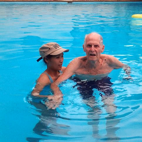 A carer helping a resident with water exercise in the pool.
