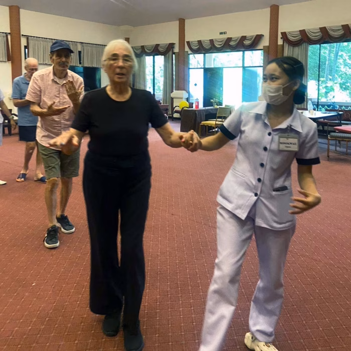 A carer and resident dancing in the function hall.