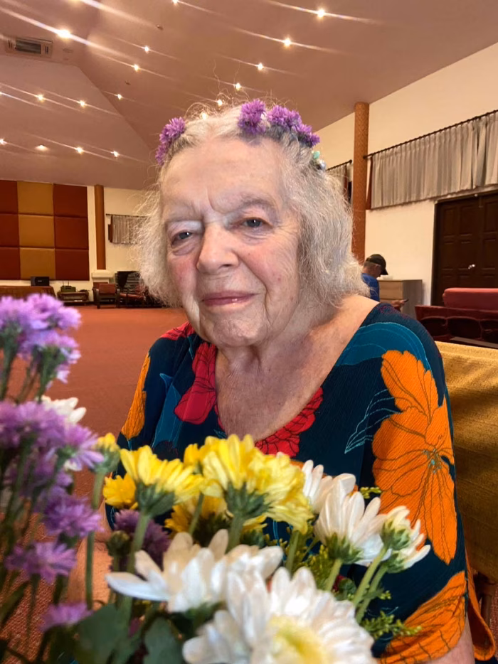 A resident with flowers in her hair, indoors.