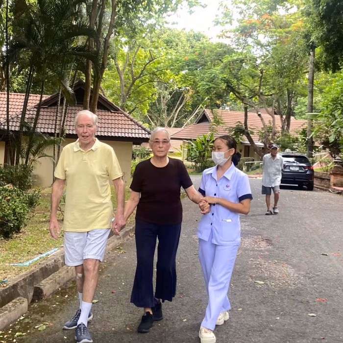 Residents and staff walking together along a garden path.