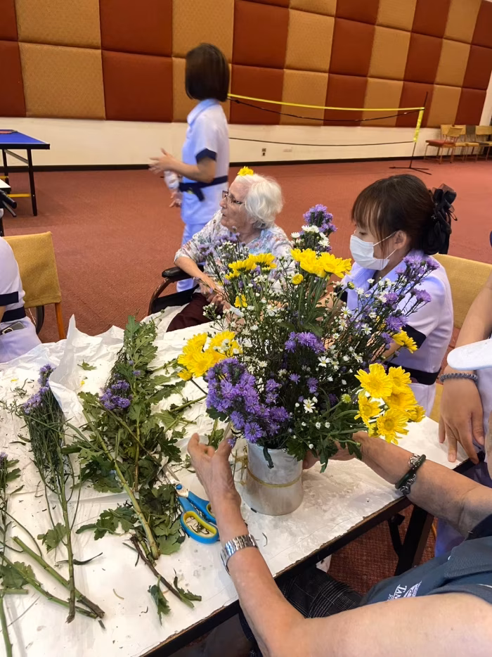 A carer and resident arranging flowers at a table.