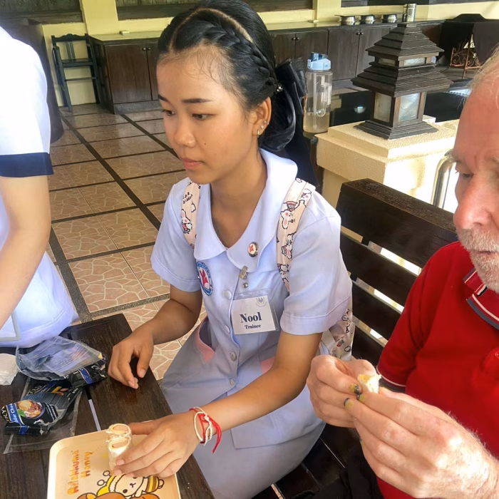 A carer helping a resident with a beading activity.