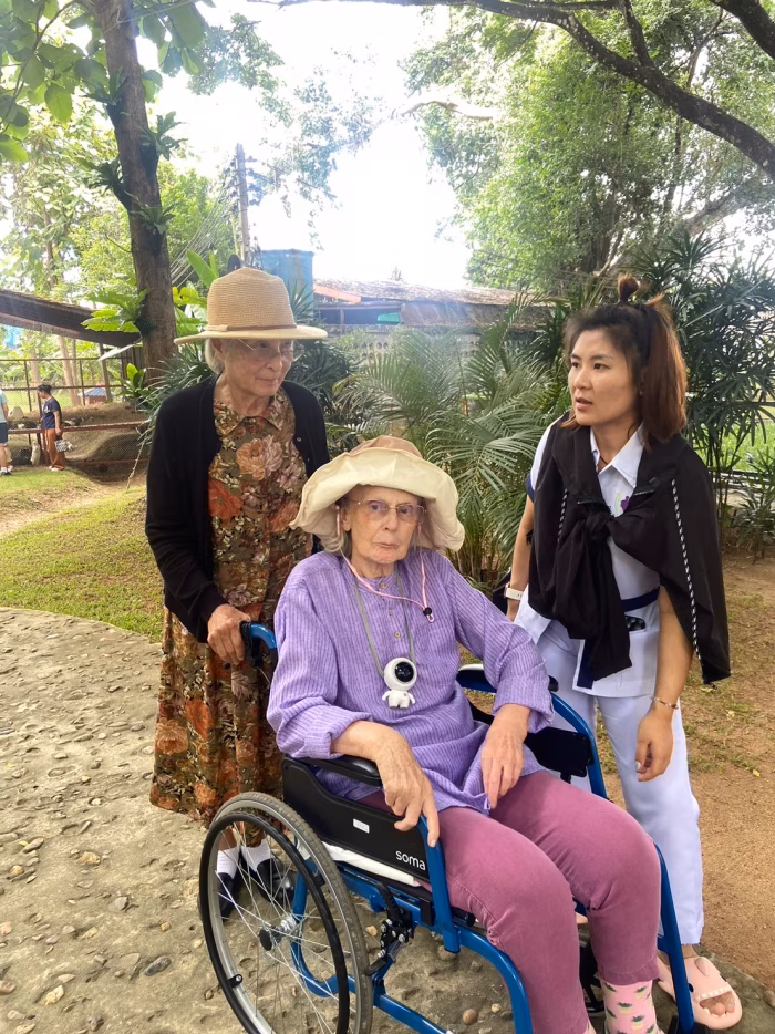A resident and carer outdoors, resident in a wheelchair.