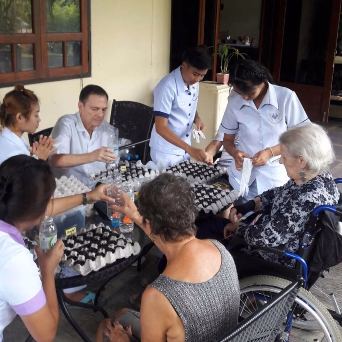 Residents and staff with craft materials at a table.