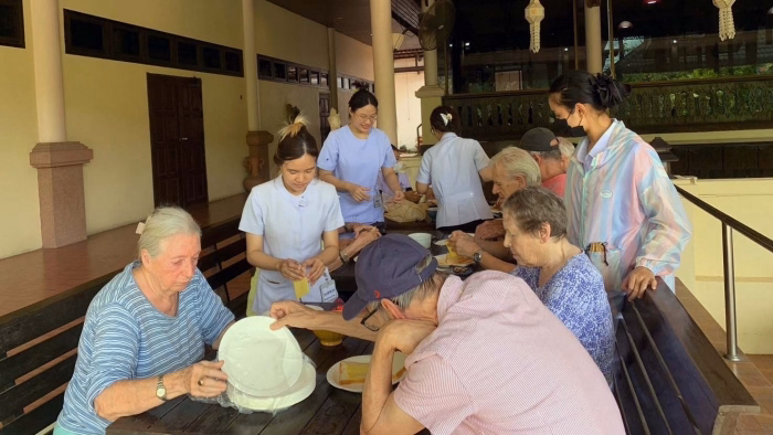 Staff and residents gathered at a table, evening light.