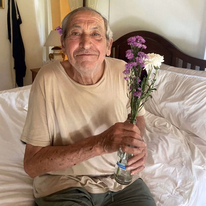 A resident in bed, holding flowers.