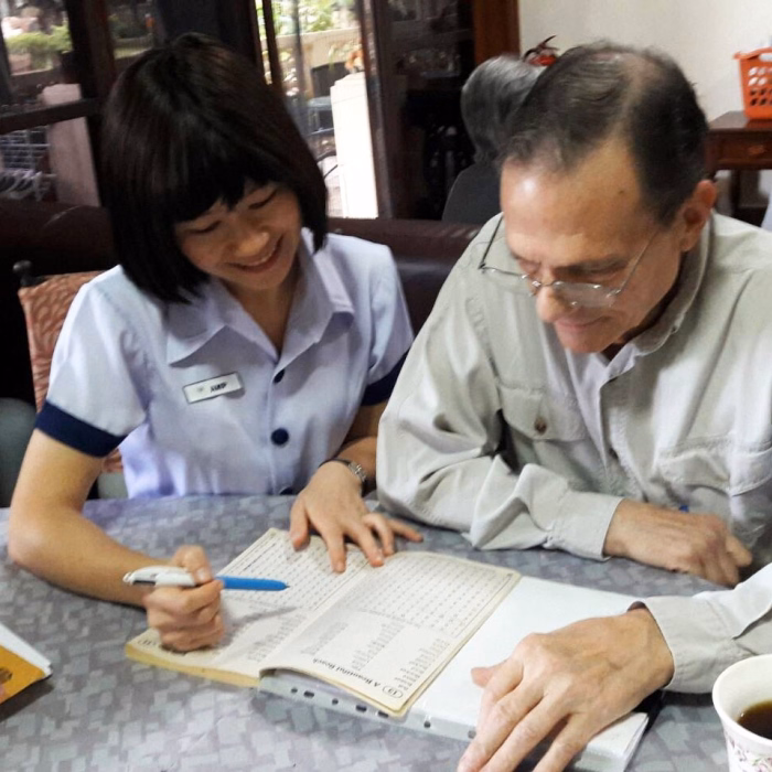 A resident and carer writing together at a table.