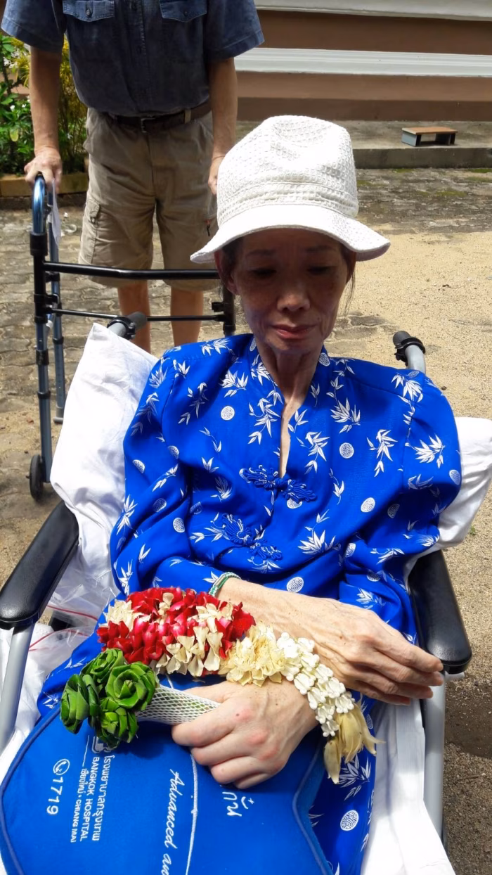 A resident in blue, seated outdoors with flowers.