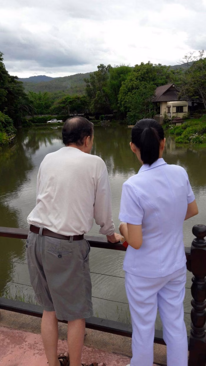 A resident and carer looking out over the lake.