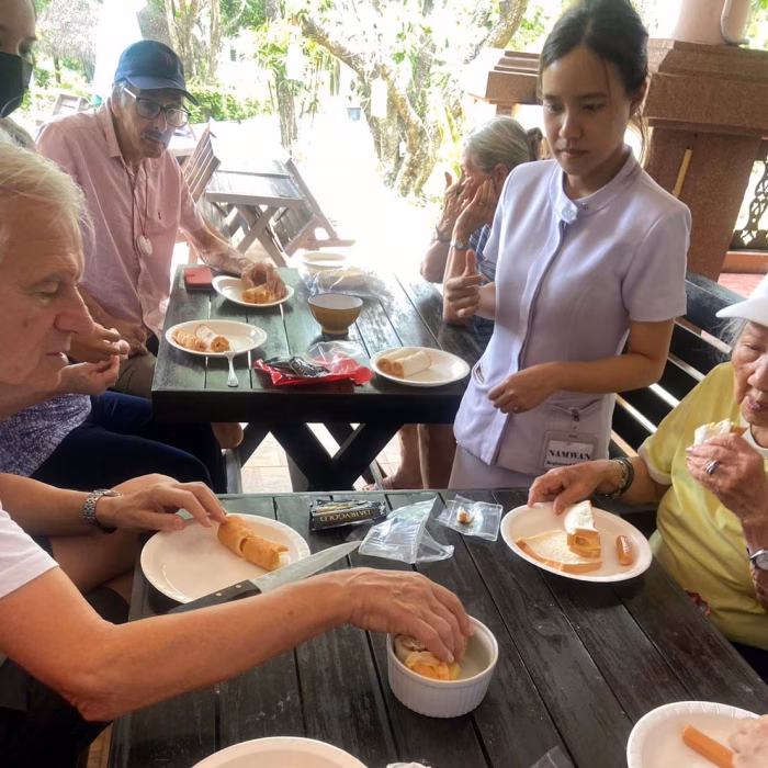 A carer serving food to residents outdoors.