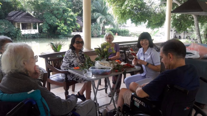 Residents and staff at an outdoor table by the lake.