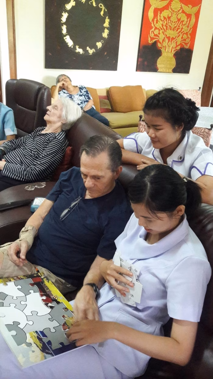 A carer helping a resident on the sofa.
