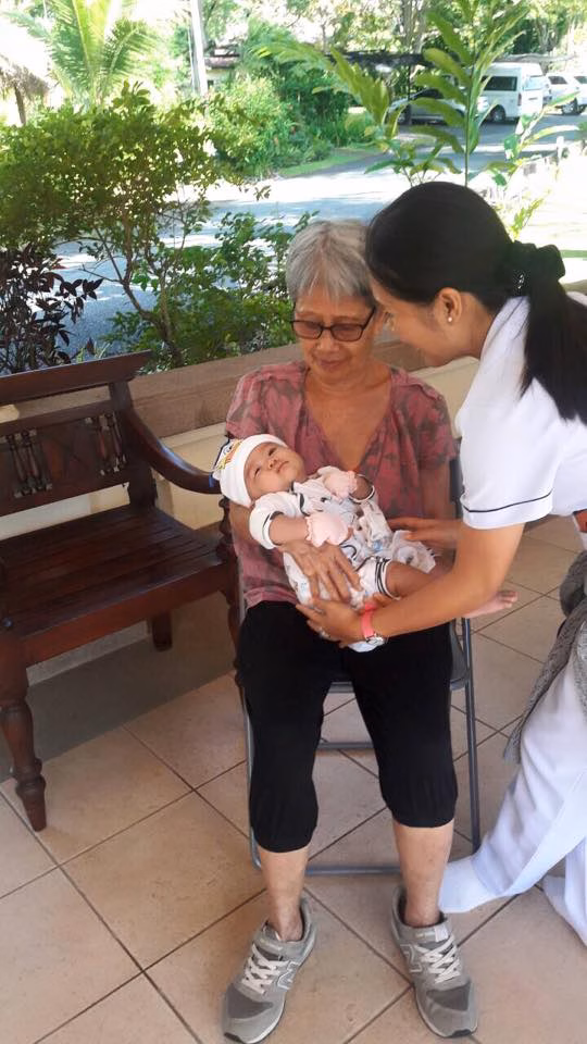 A carer bringing a small dog to visit a resident.