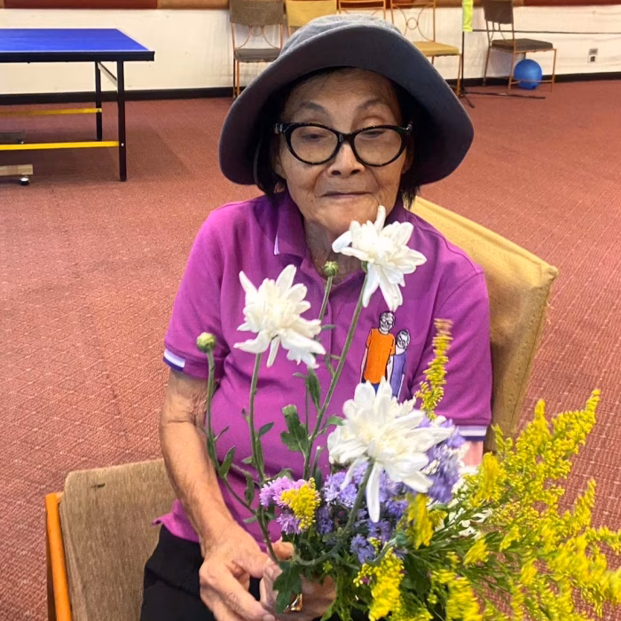 A resident holding flowers indoors.