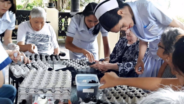Staff and residents potting seedlings into trays.