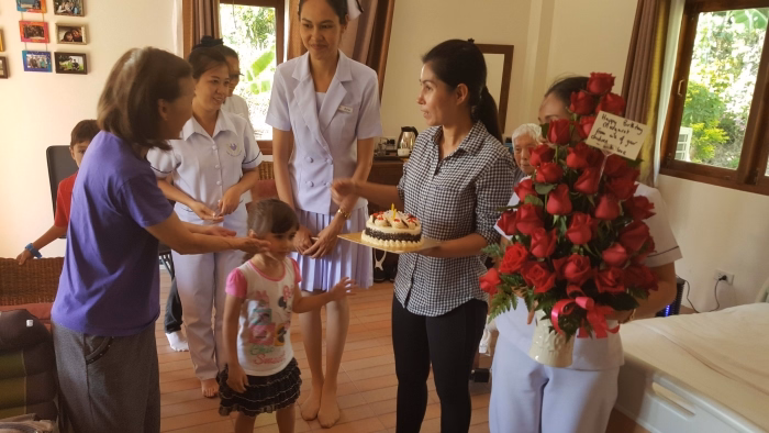 Family visiting a resident with flowers and cake.