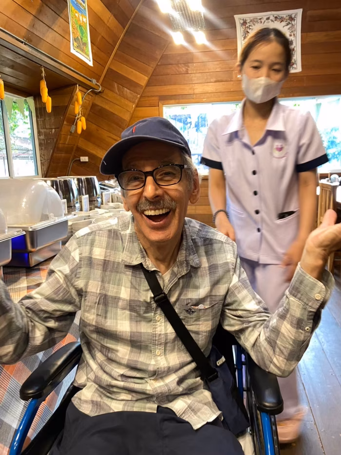 A resident in a wheelchair with a carer beside him.