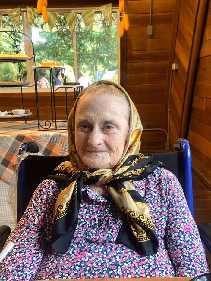 A resident in a headscarf, at an outdoor gathering.
