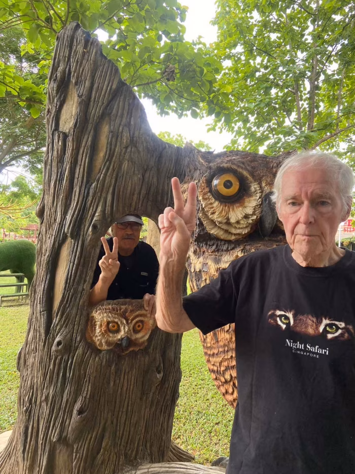 A resident beside a carved wooden owl in the garden.