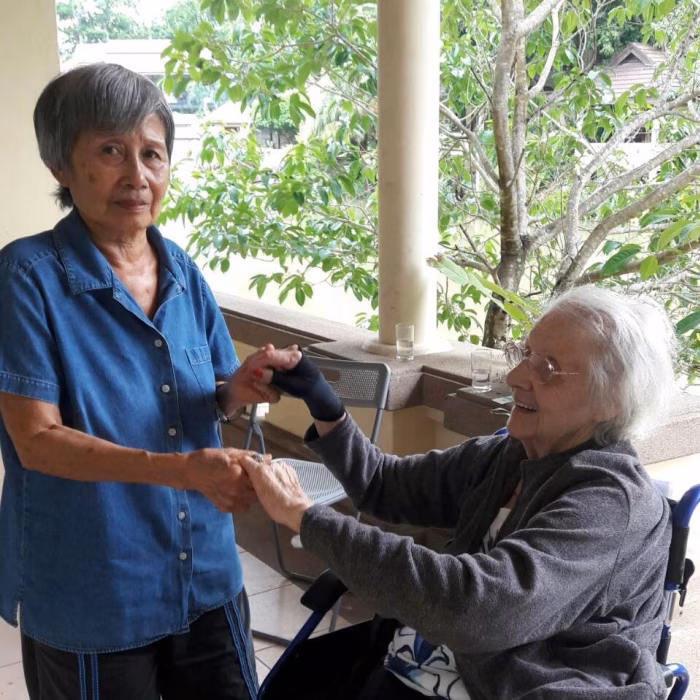 Two residents holding hands warmly on the veranda.