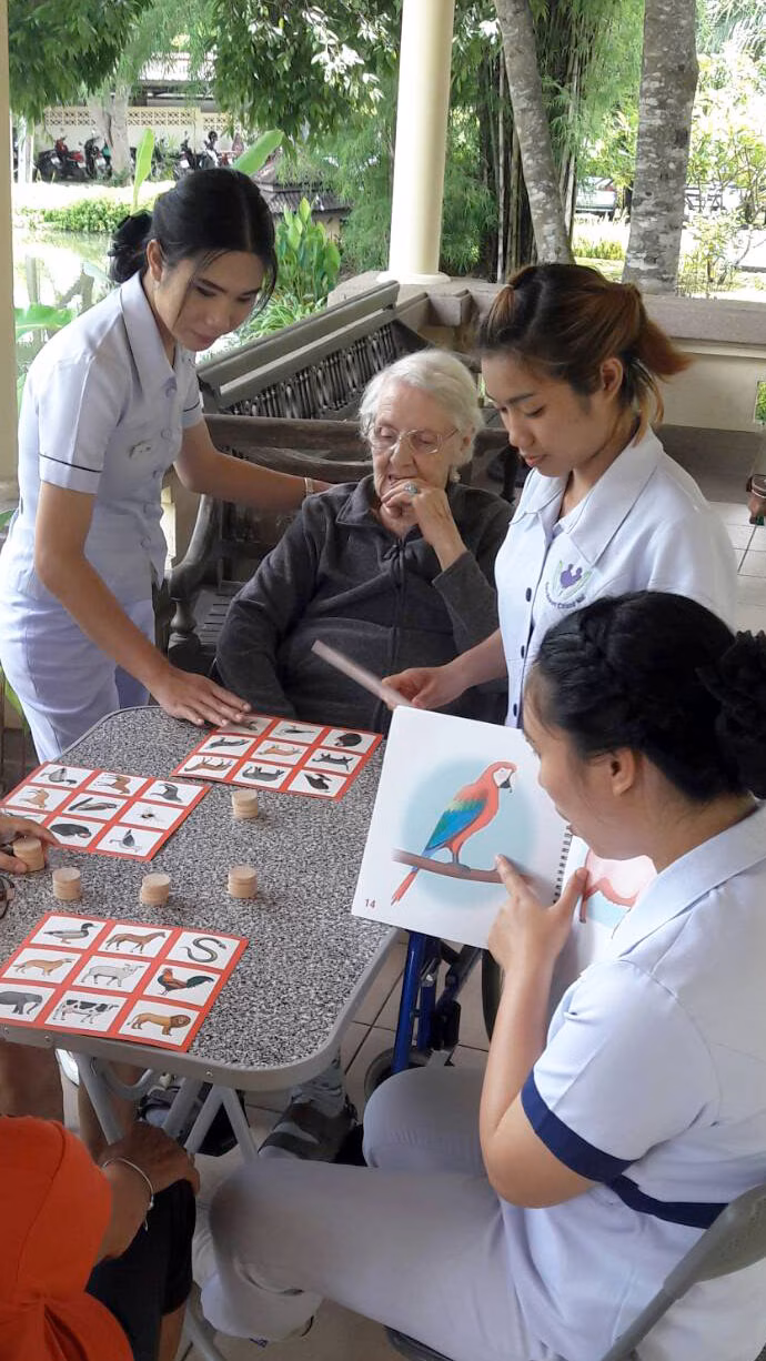 A carer helping residents with a craft table.
