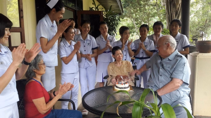 Staff applauding a resident's birthday celebration, with cake.