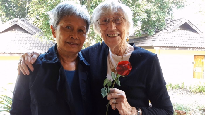 Two carers sharing an embrace, one holding a rose.