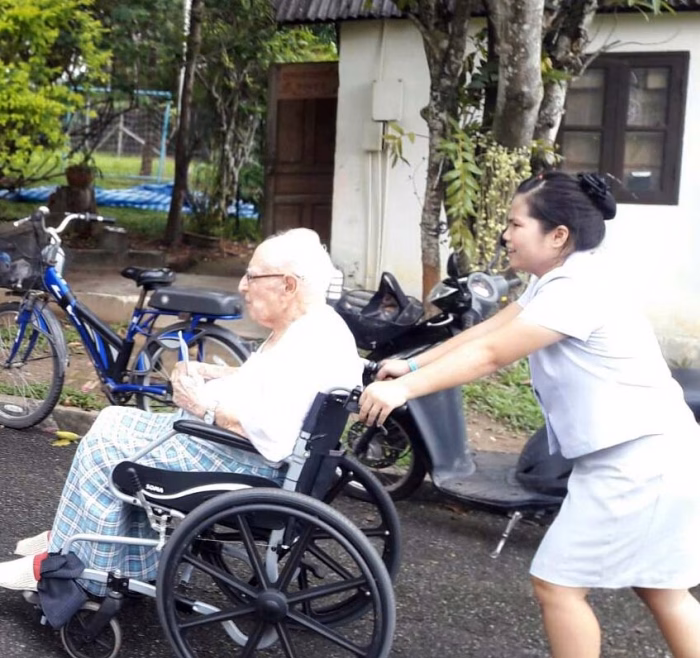 A carer with a resident in a wheelchair, a bicycle nearby.
