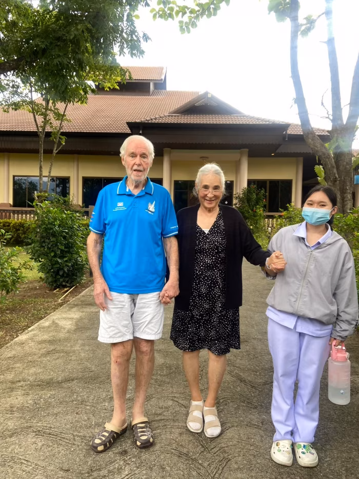 Three residents and visitors posing together outdoors.
