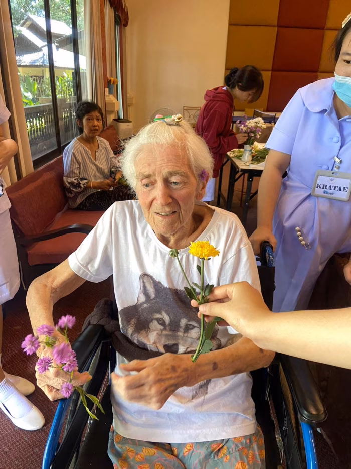 A carer offering flowers to a resident in a wheelchair.