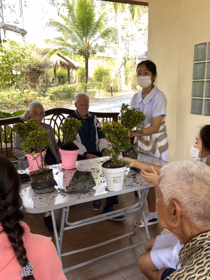 A carer serving a resident at an outdoor table.