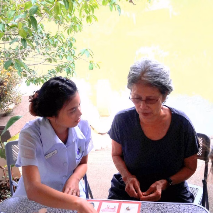 A carer helping a resident with a craft activity outdoors.