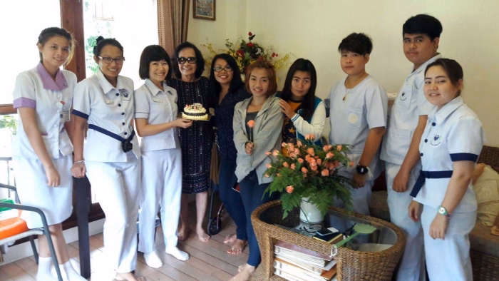 Staff and visitors gathered indoors with a bouquet of flowers.
