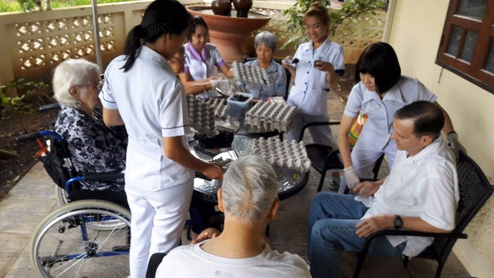 Carers helping residents in wheelchairs with a hair-styling activity.