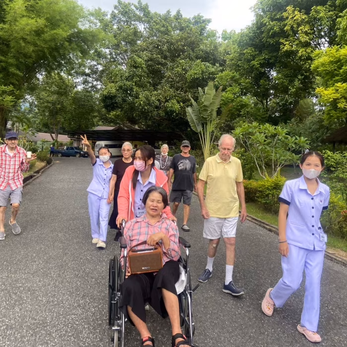 Residents walking together along a garden path with staff.