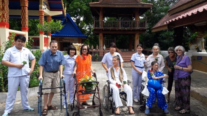 Residents, some in wheelchairs and costume, posing near a garden pavilion.