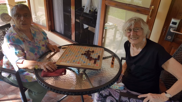 A resident and carer playing a board game at an outdoor table.