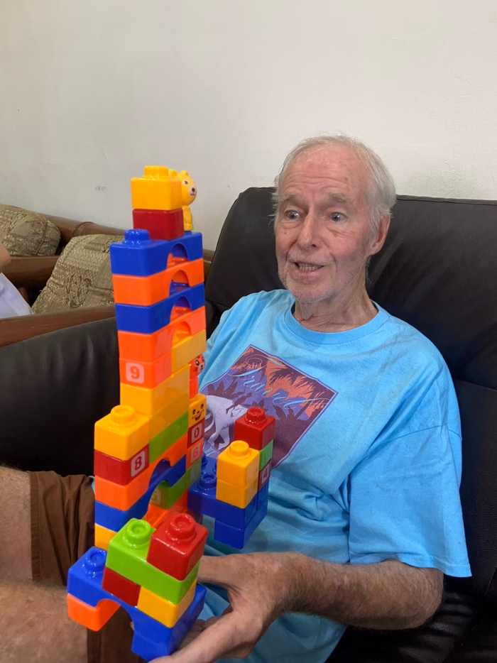A resident building a tower of coloured blocks.