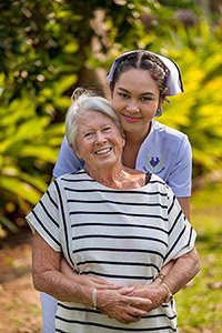 Residents and a carer talking together in the resort gardens.